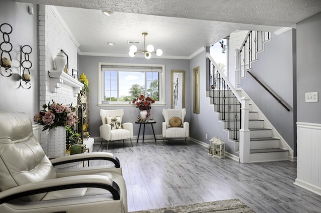 living area featuring an inviting chandelier, ornamental molding, wood finished floors, and stairway