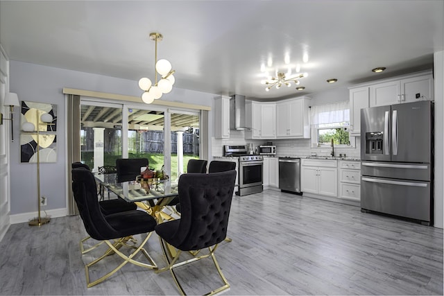dining area featuring an inviting chandelier, baseboards, and light wood-style flooring