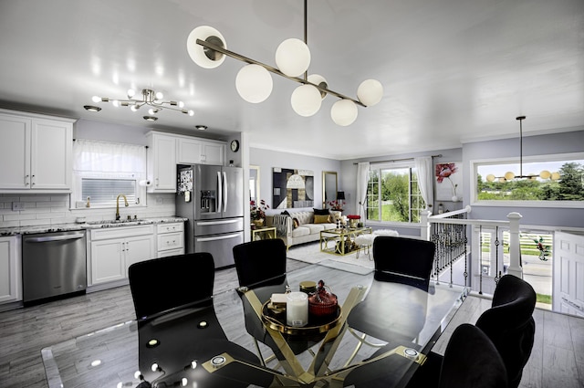 dining room with a notable chandelier, ornamental molding, and light wood-type flooring