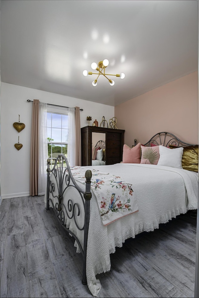 bedroom featuring baseboards, wood finished floors, and a chandelier