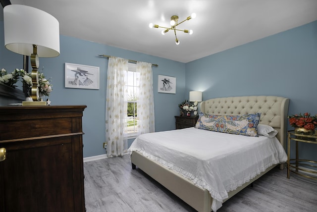 bedroom featuring baseboards, light wood finished floors, and a chandelier