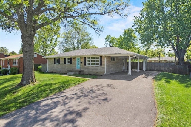 ranch-style house featuring fence, a front lawn, stone siding, aphalt driveway, and an attached carport
