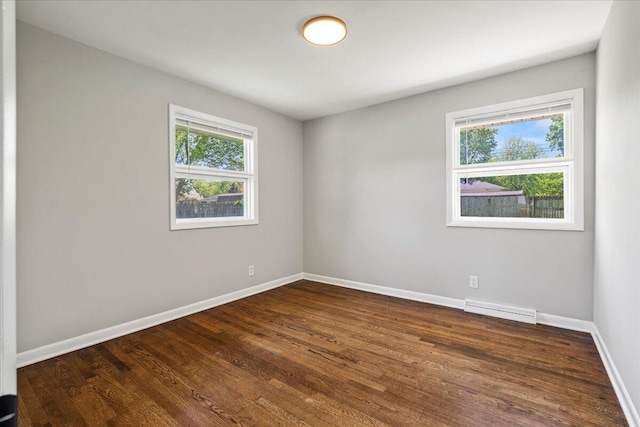 spare room featuring visible vents, baseboards, and dark wood-style flooring