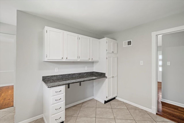 interior space with built in study area, light tile patterned floors, baseboards, and visible vents