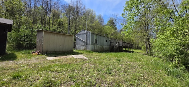 view of yard featuring an outdoor structure, a storage unit, and a deck