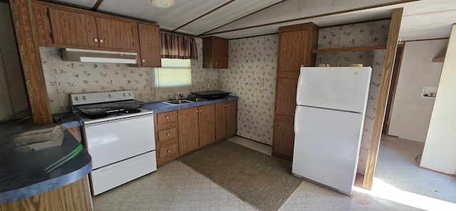 kitchen featuring light floors, wallpapered walls, vaulted ceiling, and white appliances
