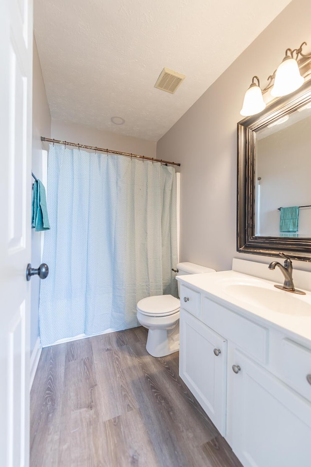 full bathroom with vanity, toilet, wood finished floors, and visible vents