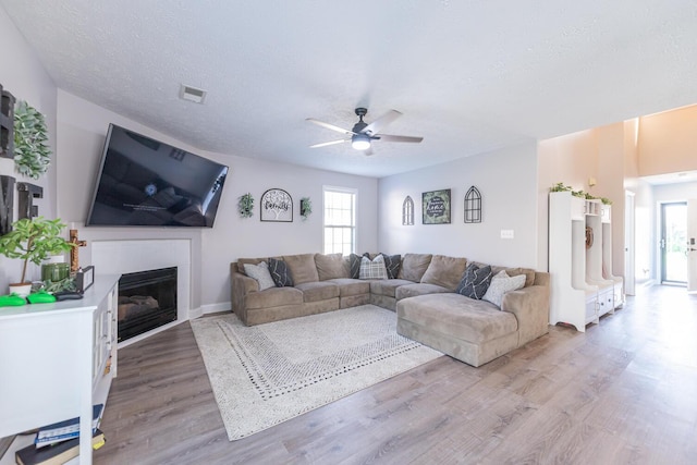 living room featuring a ceiling fan, visible vents, a wealth of natural light, and light wood finished floors