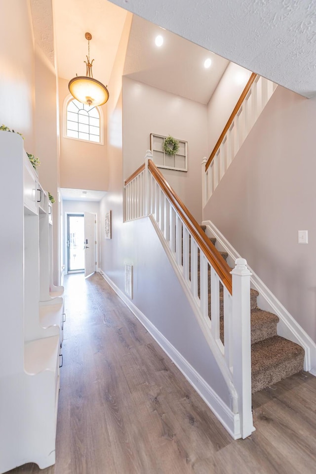 foyer with baseboards, wood finished floors, stairway, and a towering ceiling