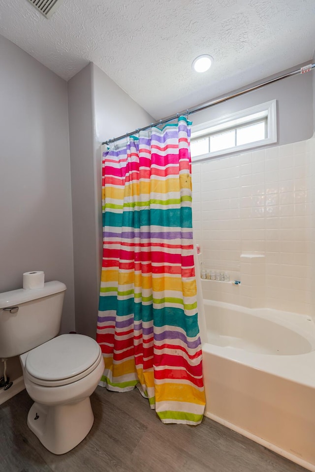 bathroom with toilet, a textured ceiling, and wood finished floors