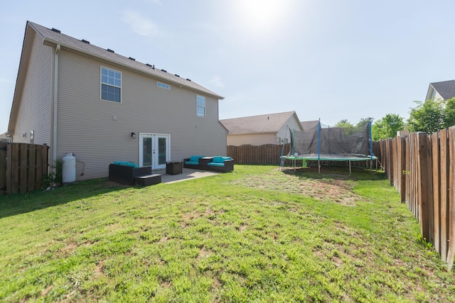 back of property with a trampoline, an outdoor hangout area, a fenced backyard, french doors, and a yard