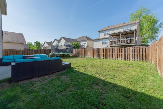 view of yard with a residential view, a trampoline, an outdoor living space, and a fenced backyard