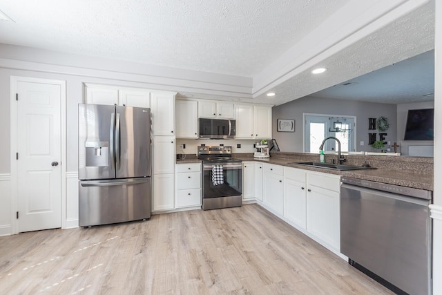 kitchen with recessed lighting, white cabinetry, a sink, light wood-style flooring, and stainless steel appliances