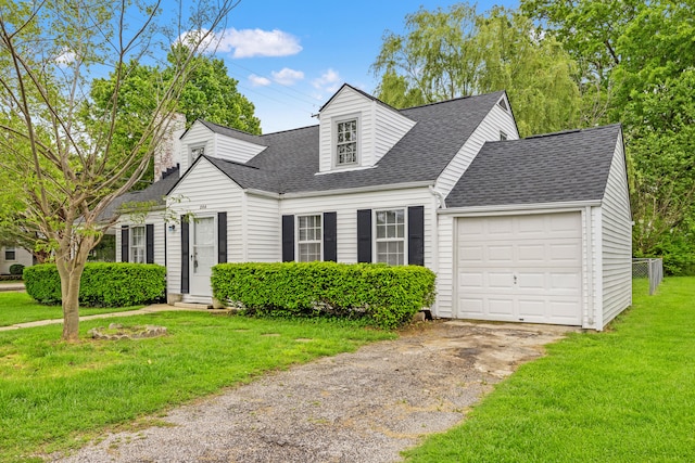 new england style home with a shingled roof, driveway, an attached garage, and a front lawn