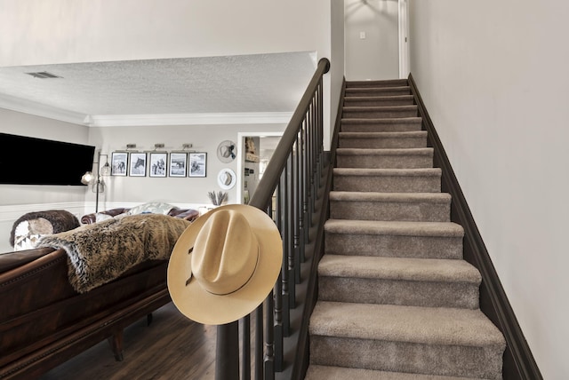 stairs with visible vents, ornamental molding, a textured ceiling, and wood finished floors