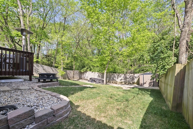 view of yard featuring a fenced backyard, a storage unit, and an outdoor structure