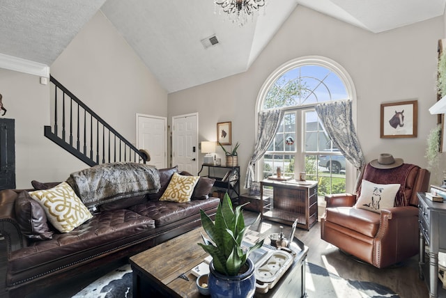 living area with visible vents, high vaulted ceiling, wood finished floors, and stairway
