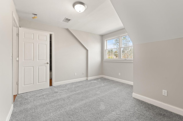 additional living space with carpet floors, baseboards, lofted ceiling, and visible vents
