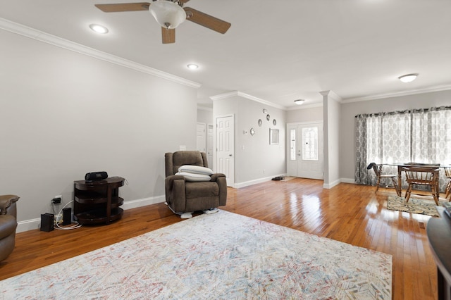 living area with baseboards, crown molding, ceiling fan, and wood finished floors