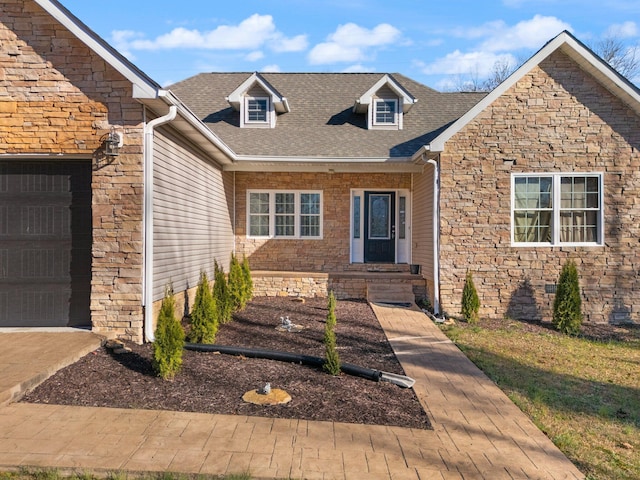 view of front of house with an attached garage, a shingled roof, and stone siding
