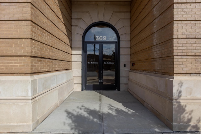 view of exterior entry with brick siding and french doors