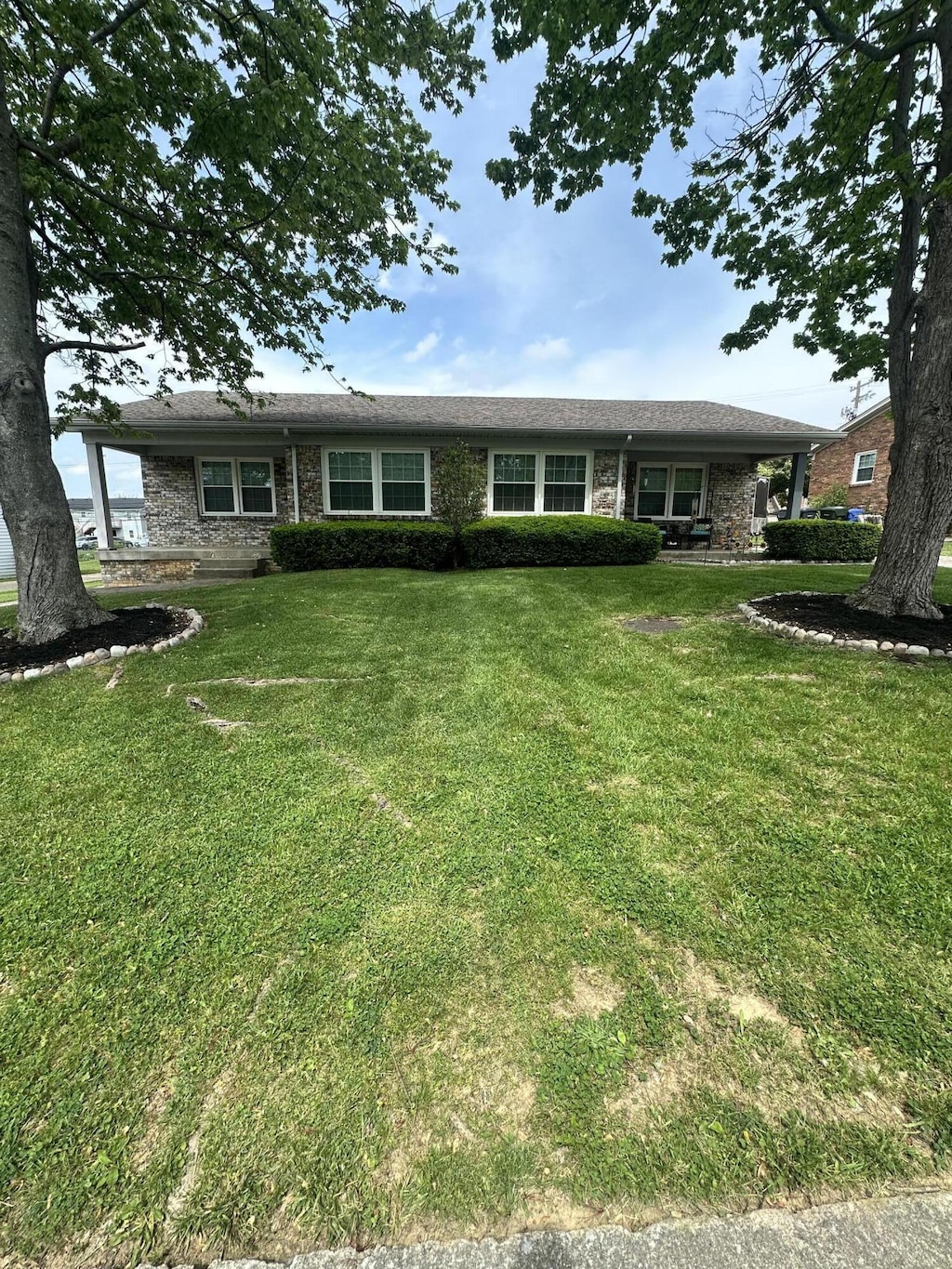 ranch-style house featuring brick siding and a front yard
