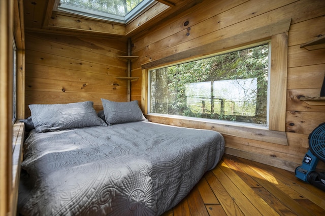 bedroom featuring multiple windows, wooden walls, and a skylight
