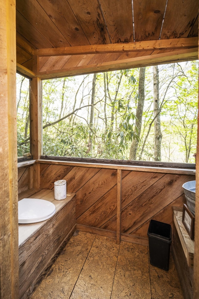 bathroom featuring a wealth of natural light, wood ceiling, and a tub to relax in