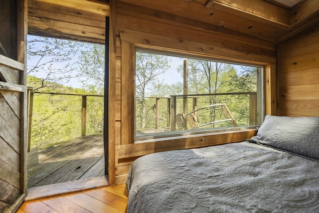 bedroom featuring wood walls, wood finished floors, and multiple windows