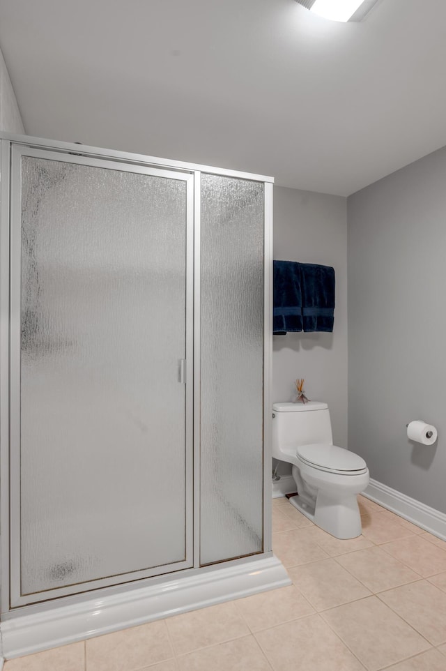 full bathroom featuring baseboards, tile patterned flooring, a shower stall, and toilet