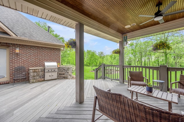 wooden deck with an outdoor kitchen, a ceiling fan, a lawn, and grilling area