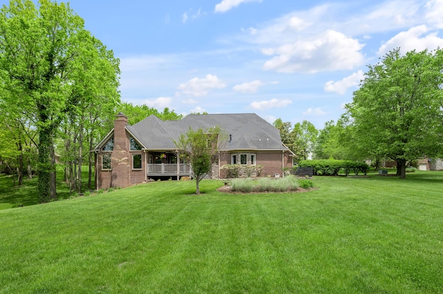 back of property featuring a shingled roof, a chimney, and a yard