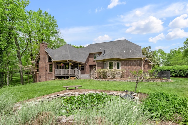 rear view of property with a yard, a deck, a chimney, and brick siding
