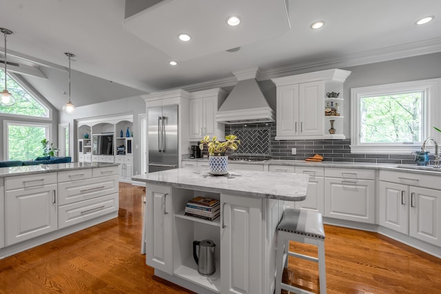 kitchen with open shelves, stainless steel appliances, white cabinetry, custom range hood, and a kitchen island