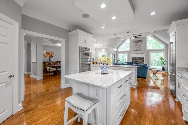kitchen with a glass covered fireplace, a peninsula, open floor plan, a center island, and a ceiling fan