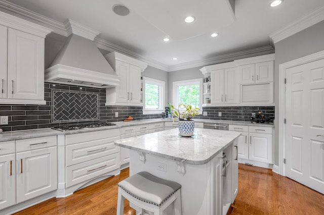 kitchen with a center island, tasteful backsplash, appliances with stainless steel finishes, premium range hood, and white cabinetry