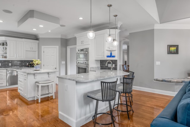 kitchen with appliances with stainless steel finishes, tasteful backsplash, open shelves, and a breakfast bar area