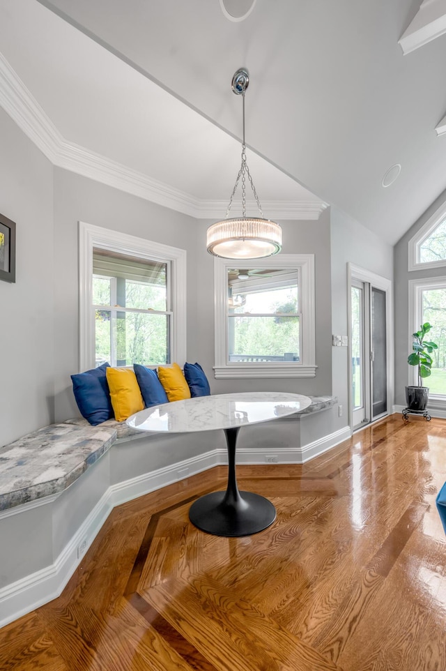 dining room featuring crown molding, breakfast area, baseboards, wood finished floors, and lofted ceiling