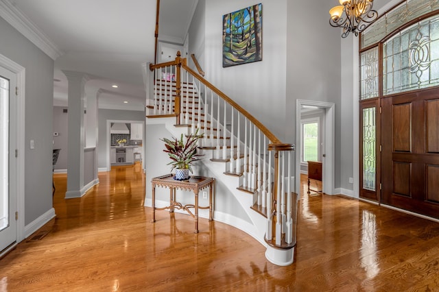 entrance foyer with crown molding, a chandelier, stairs, baseboards, and wood finished floors