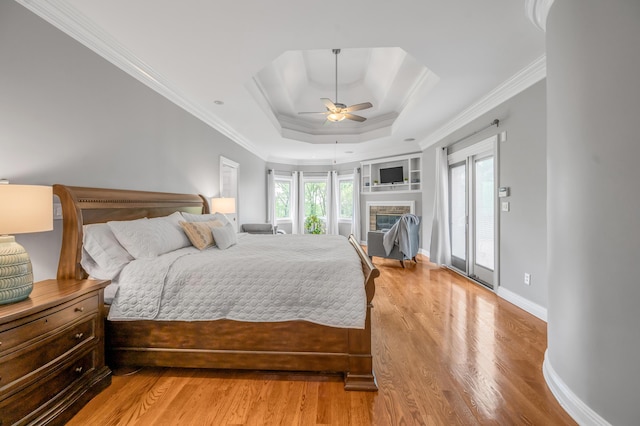 bedroom featuring crown molding, access to outside, a raised ceiling, baseboards, and light wood-type flooring