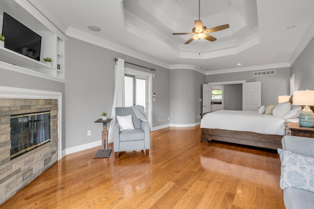 bedroom with crown molding, a tray ceiling, visible vents, and light wood-style floors