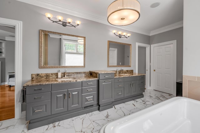 full bathroom with double vanity, a freestanding bath, a sink, and marble finish floor