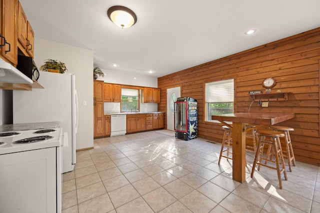 kitchen with plenty of natural light, brown cabinetry, light tile patterned flooring, and white appliances