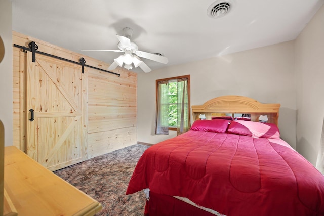 bedroom featuring carpet floors, a barn door, ceiling fan, and visible vents