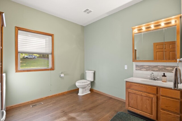 bathroom with baseboards, backsplash, wood finished floors, and visible vents