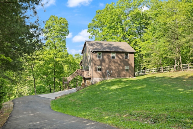 view of side of property with fence, stairs, a lawn, and a deck