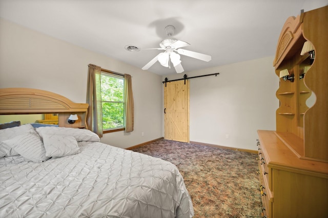 carpeted bedroom with baseboards, ceiling fan, a barn door, and visible vents