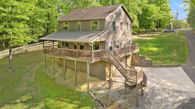 rear view of house featuring a wooden deck, fence, a shingled roof, a lawn, and stairway