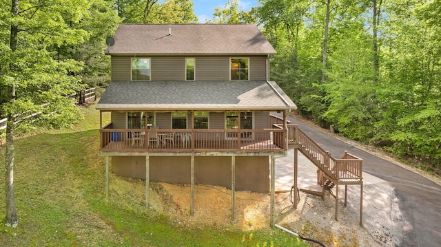 back of house with a lawn, roof with shingles, and a deck