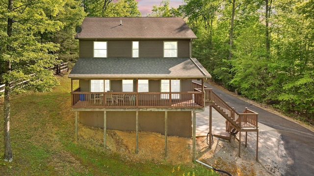 rear view of property featuring a wooden deck and a shingled roof